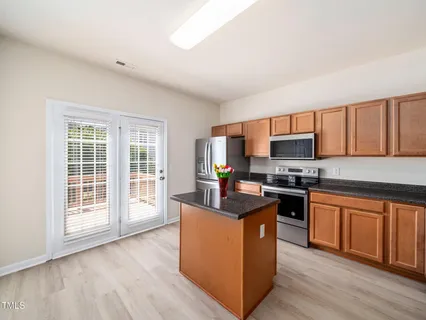 a kitchen with stainless steel appliances granite countertop a stove top oven a sink dishwasher a refrigerator and a microwave oven with wooden floors
