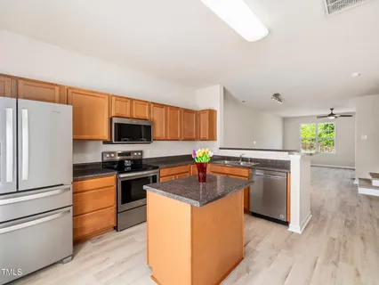 a kitchen with stainless steel appliances granite countertop a refrigerator a stove a sink and a microwave