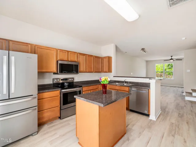 a kitchen with stainless steel appliances granite countertop a refrigerator a stove a sink and a microwave