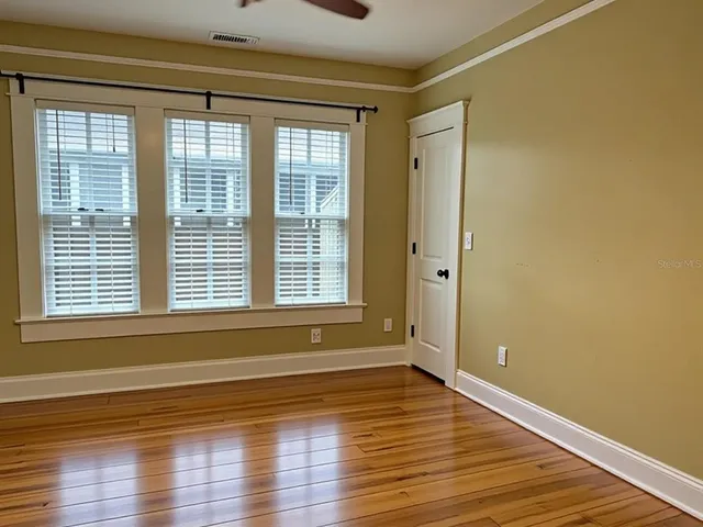 a view of empty room with wooden floor and fan