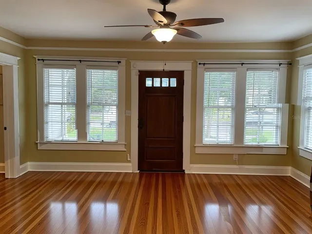 a view of an empty room with wooden floor and a window