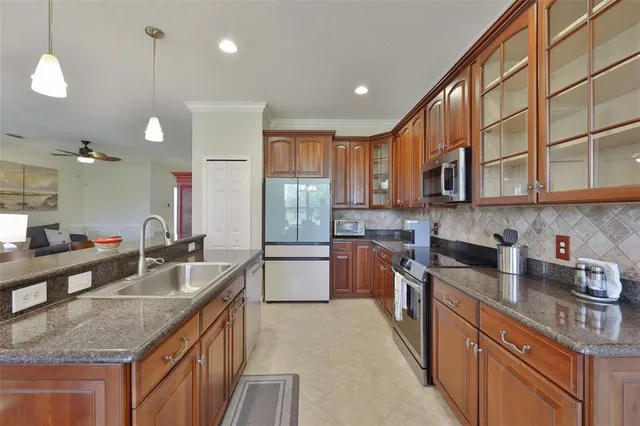 a kitchen with stainless steel appliances granite countertop a sink a stove and a wooden cabinets