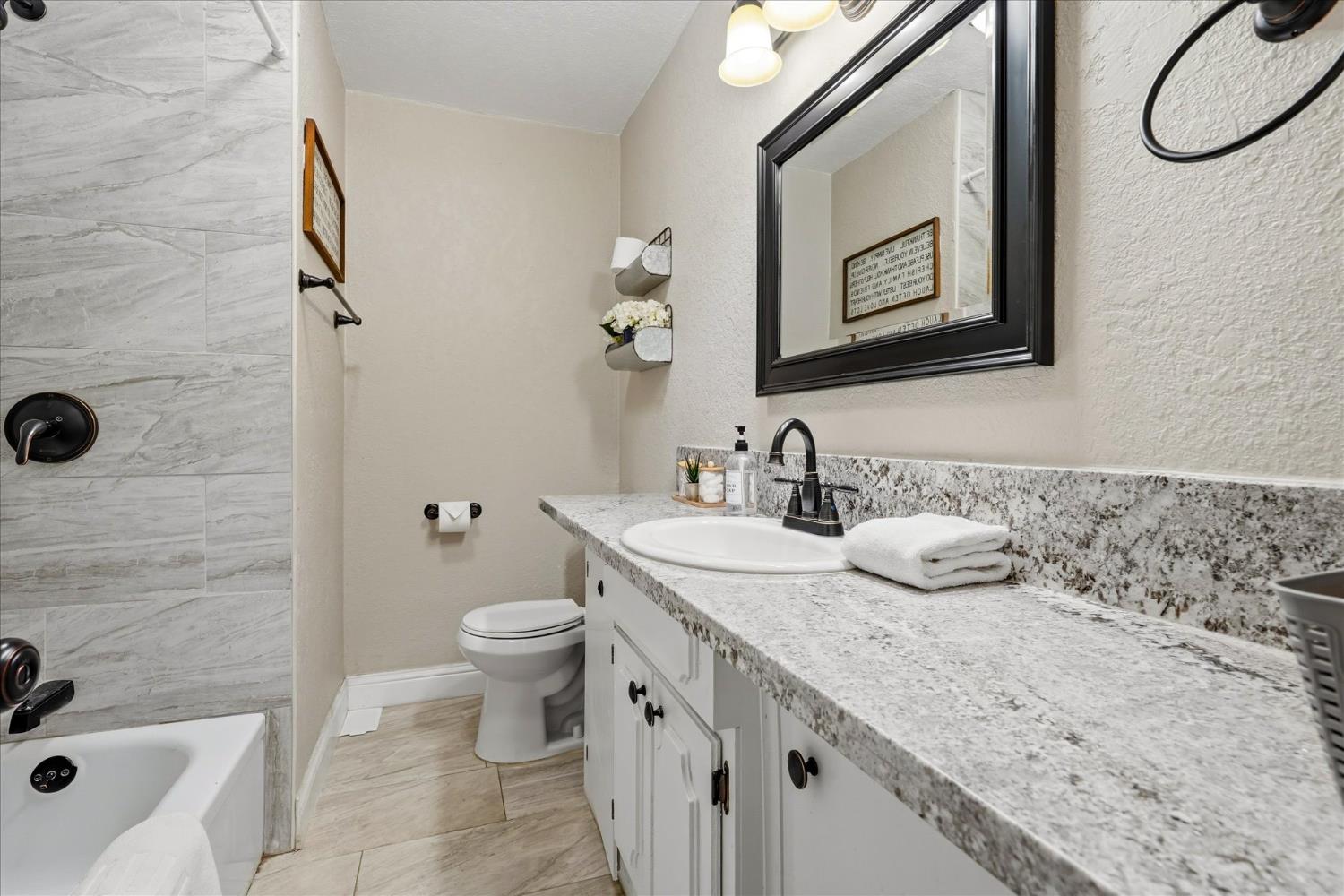 50740 Chu Ranch Road Oakhurst, CA 93644 - Photo 19 of 37 a bathroom with a granite countertop sink a toilet and shower