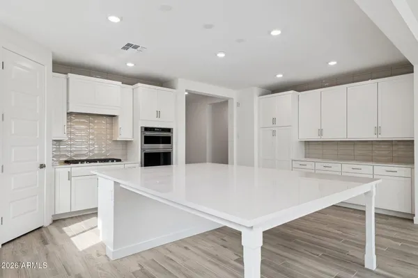 a large kitchen with stainless steel appliances a large counter top and a stove top oven