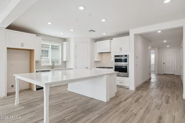 a large white kitchen with lots of counter space a sink appliances and cabinets
