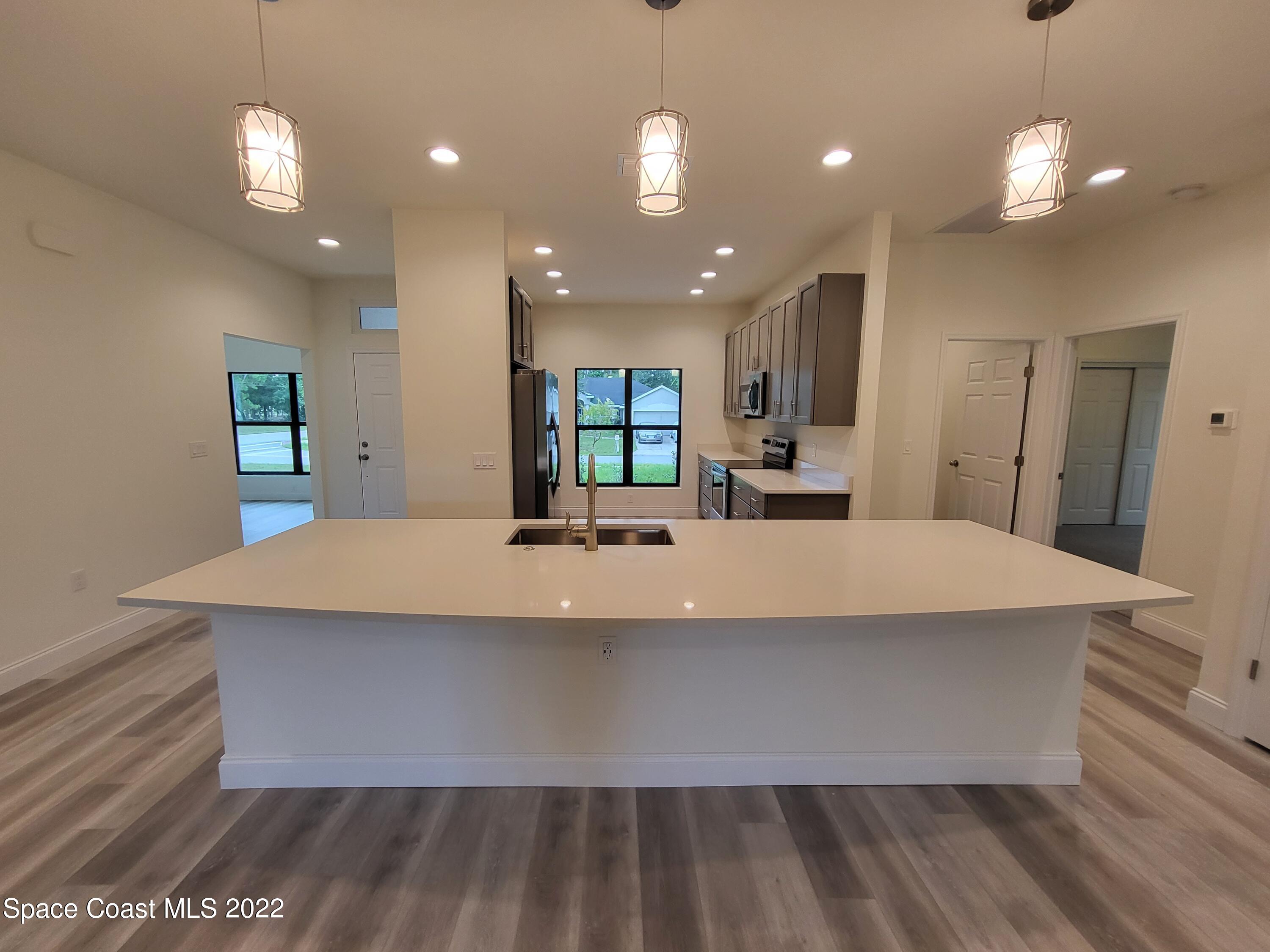 1231 Sexton Road Southwest Palm Bay, FL 32908 - Photo 8 of 36 a large kitchen with kitchen island a sink stainless steel appliances and cabinets