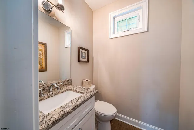 a bathroom with a granite countertop toilet sink and mirror