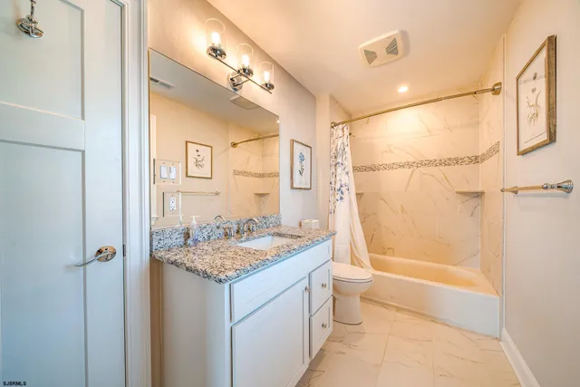 a bathroom with a granite countertop sink toilet and shower