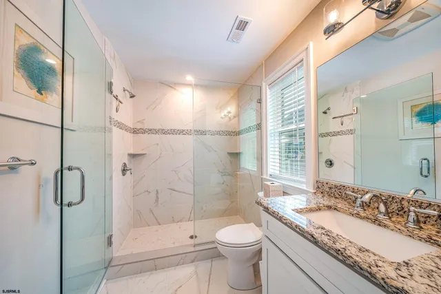 a bathroom with a granite countertop sink toilet and shower