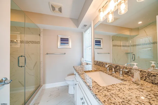 a bathroom with a granite countertop sink mirror vanity and toilet