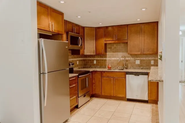 a kitchen with stainless steel appliances granite countertop a refrigerator a sink and dishwasher