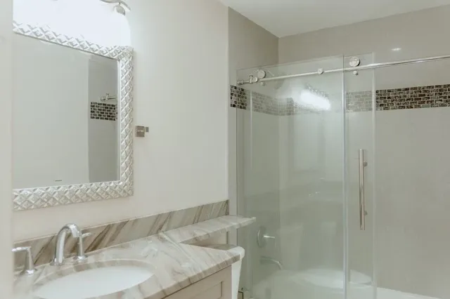a bathroom with a granite countertop shower sink and mirror