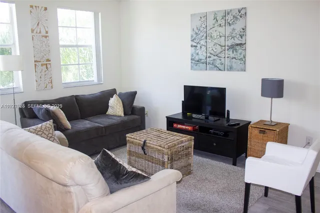 a living room with furniture a flat screen tv and a window