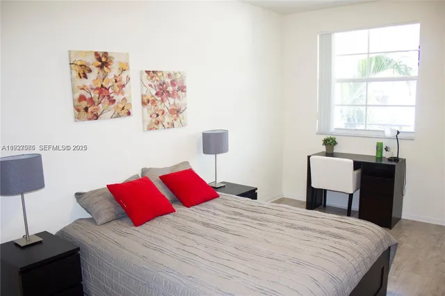 a bedroom with a bed and a lamp on dresser