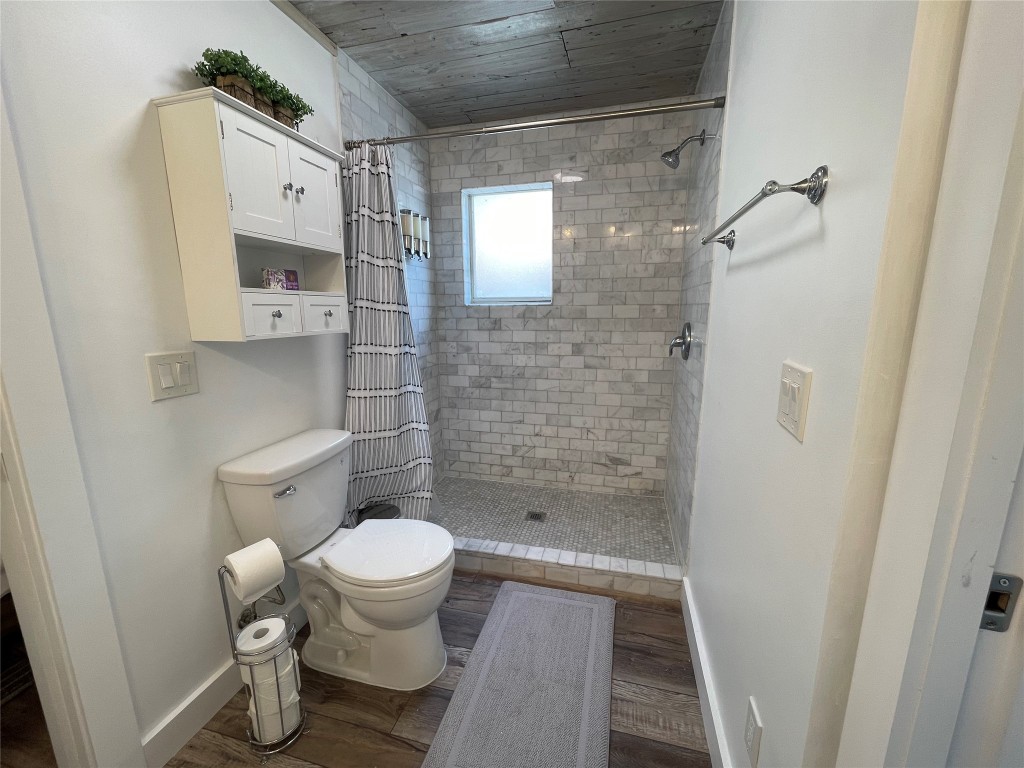 2402 Santa Rita Street Austin, TX 78702 - Photo 12 of 17 Bathroom featuring a stall shower, dark wood finished floors, and wooden ceiling
