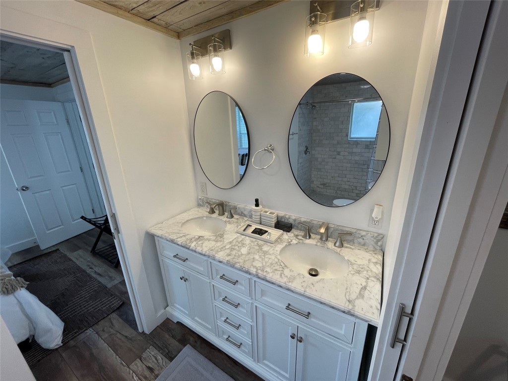 2402 Santa Rita Street Austin, TX 78702 - Photo 10 of 17 Bathroom with dark wood-style floors, double vanity, and a tile shower