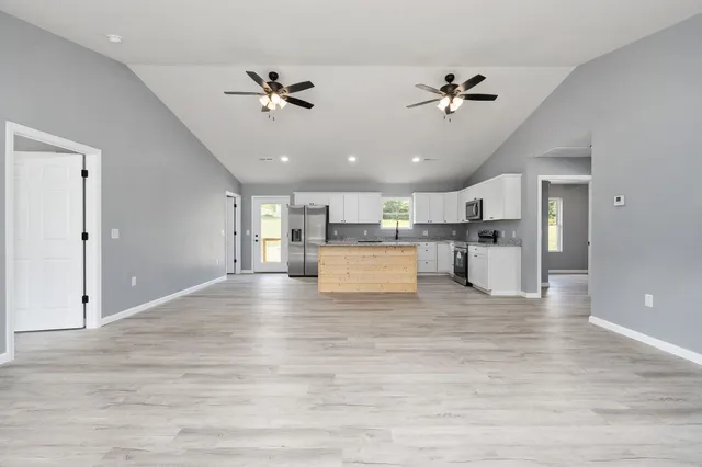 a view of a living room a ceiling fan and kitchen view