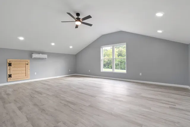 an empty room with wooden floor ceiling fan and window