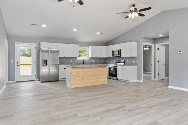 a view of kitchen with granite countertop stainless steel appliances cabinets a sink and a counter top space