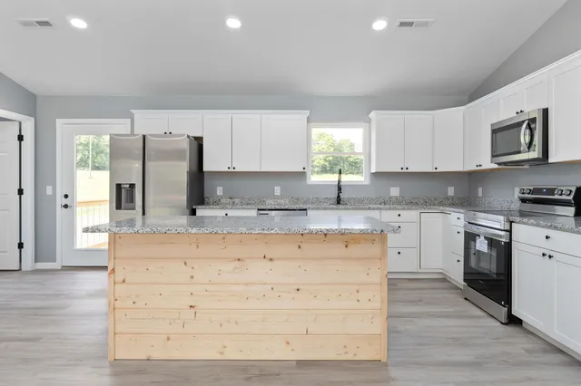 a kitchen with granite countertop cabinets stainless steel appliances a sink and a window