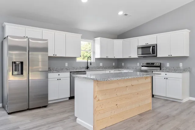 a kitchen with granite countertop white cabinets and stainless steel appliances
