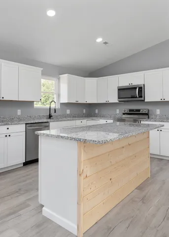 a kitchen with stainless steel appliances granite countertop a sink a stove a refrigerator and cabinets