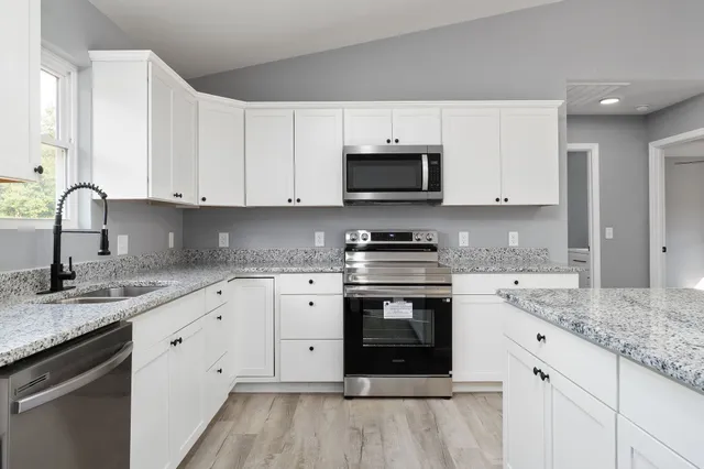 a kitchen with granite countertop white cabinets stainless steel appliances and a sink