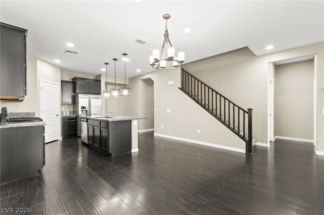 11048 Prairie Grove Road Las Vegas, NV 89179 - Photo 17 of 75 An open concept design seamlessly connects the kitchen and living area, featuring rich dark hardwood flooring.