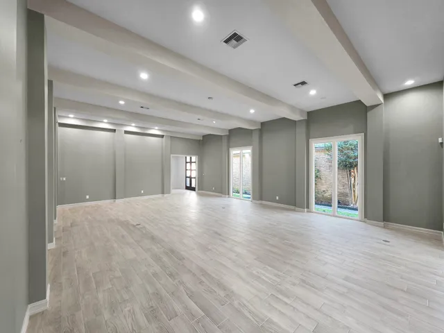 an empty room with wooden floor chandelier fan and windows