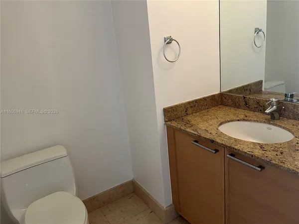 a bathroom with a granite countertop sink toilet and a mirror