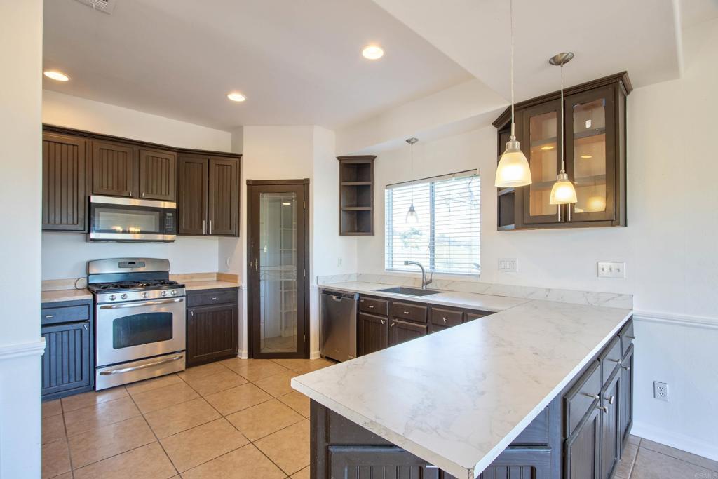 a kitchen with stainless steel appliances granite countertop a sink a stove a refrigerator cabinets and a dining table