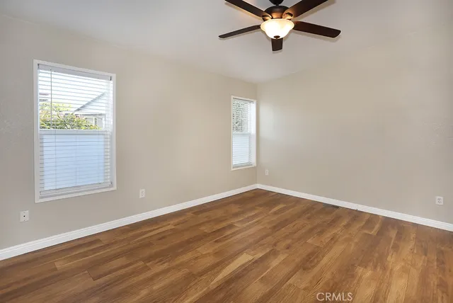 a view of empty room with wooden floor and fan