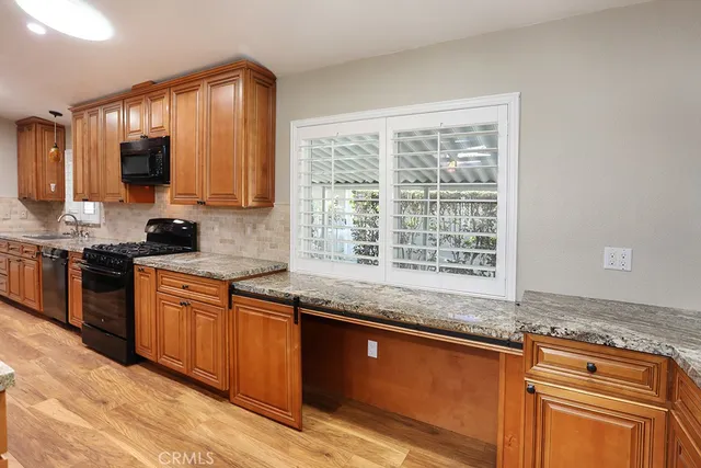 a kitchen with stainless steel appliances granite countertop wooden cabinets a stove a sink and a window
