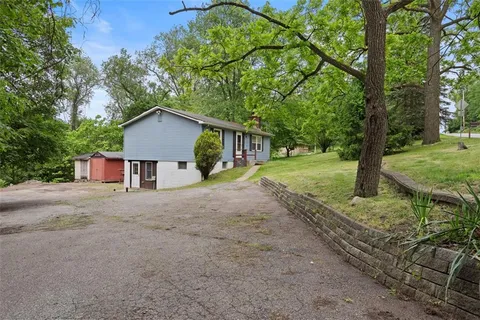 a view of a house with a yard and large tree