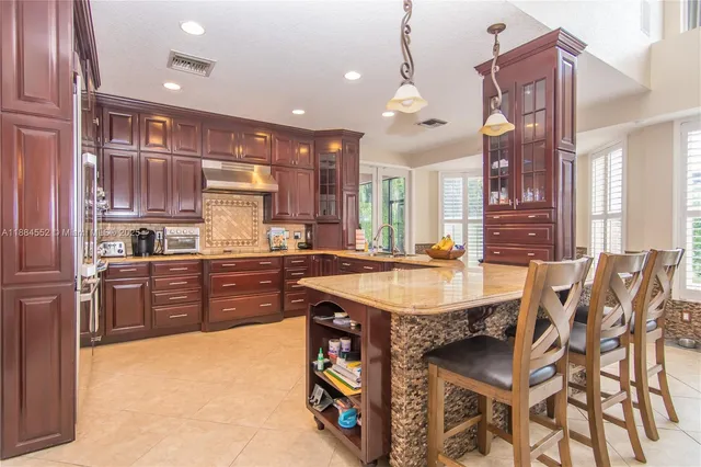 a kitchen with stainless steel appliances granite countertop a table chairs sink and cabinets