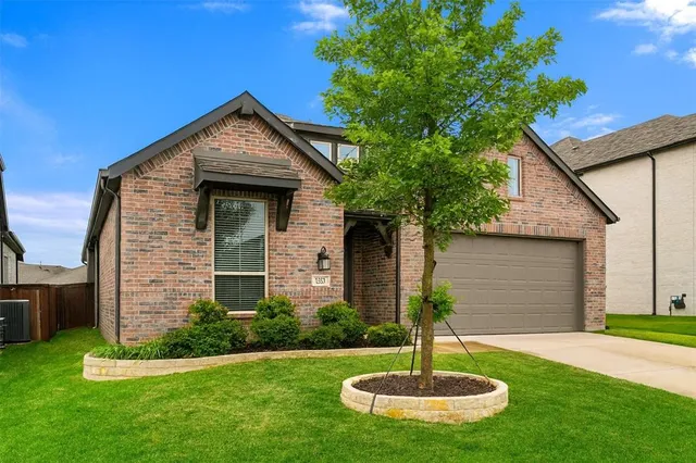 a front view of a house with a yard and a large tree