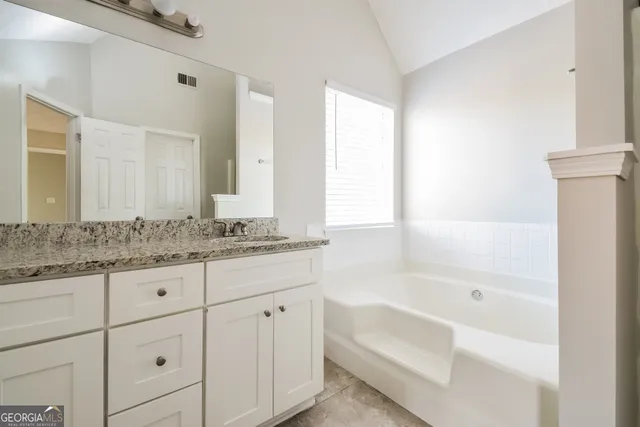 a bathroom with a granite countertop sink a mirror and a bathtub