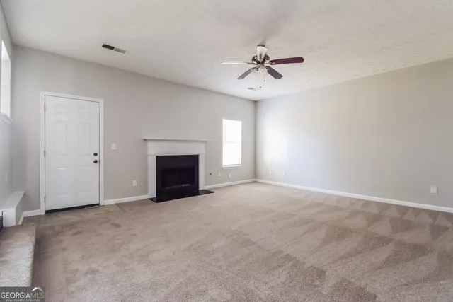 a view of an empty room with a fireplace and a window
