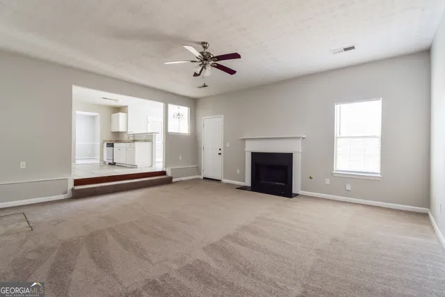 an empty room with windows and fireplace