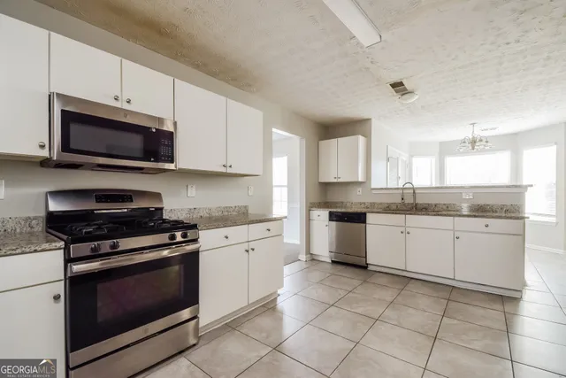 a kitchen with granite countertop white cabinets a sink and white appliances