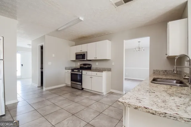 a kitchen with granite countertop a sink stove and refrigerator