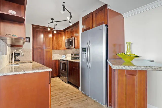 a kitchen with stainless steel appliances granite countertop a sink a refrigerator and a stove