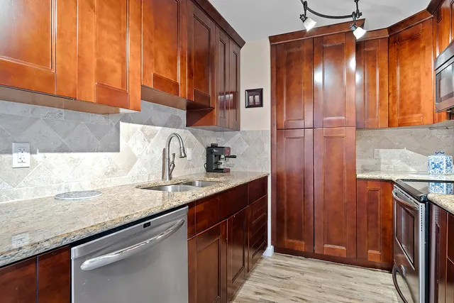 a kitchen with stainless steel appliances granite countertop wooden cabinets and sink