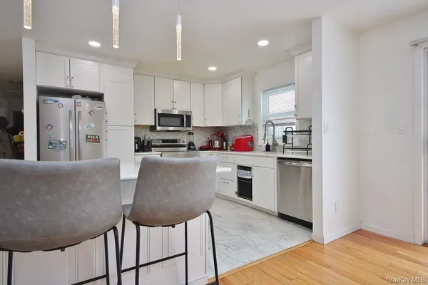 a kitchen with stainless steel appliances granite countertop a refrigerator a stove a sink and a microwave with wooden floor