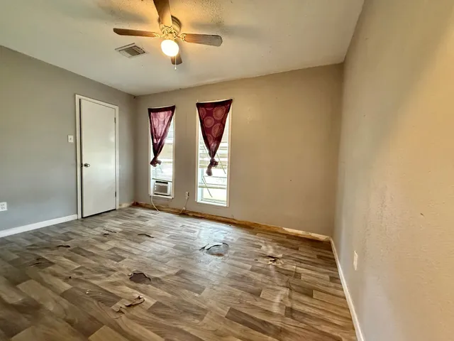 a view of an empty room and window and chandelier fan