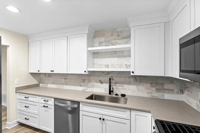 a kitchen with cabinets appliances a sink and a window