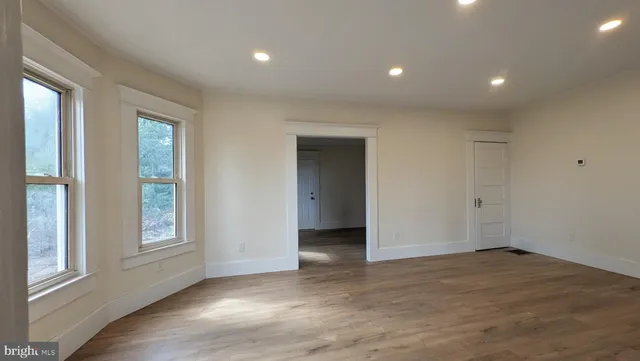 a view of an empty room with a window and wooden floor