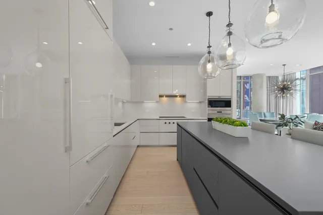 a large white kitchen with lots of counter space and a chandelier