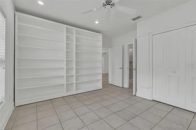an empty room with wooden floor chandelier fan and windows