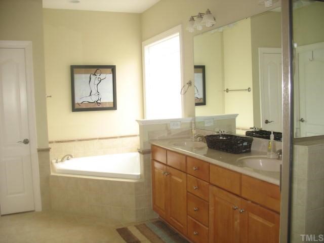10311 Evergreen Spring Place Raleigh, NC 27614 - Photo 7 of 12 Luxurious and spa like - this master bath features a raised vanity, upgraded lighting and plumbing fixtures, a separate tiled shower and a deep soaking tub with glass block window.